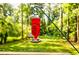 View of the backyard with a decorative red bird feeder hanging with natural light and green trees at 2343 Hunting Valley Dr, Decatur, GA 30033