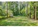 Lush backyard with mature trees, a small storage building and a fenced in play area at 2343 Hunting Valley Dr, Decatur, GA 30033