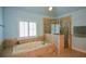 Bathroom with jetted tub, shower, tiled surround, and plantation shutters at 3423 Mulberry Lane Ct, Dacula, GA 30019