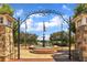 Entrance to Lillian Webb Park featuring a stone archway, flags, and a serene water fountain at 659 Holcomb Bridge Rd, Norcross, GA 30071