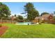 Lush backyard with a sparkling pool, surrounded by green grass and mature trees at 4045 Boles Creek Dr, Duluth, GA 30096