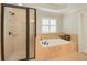 Bright bathroom featuring a soaking tub, stone tile surround, and glass-enclosed shower at 4045 Boles Creek Dr, Duluth, GA 30096