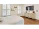 Sunlit bedroom featuring wood floors, plantation shutters, and a classic dresser with a mounted television at 4045 Boles Creek Dr, Duluth, GA 30096
