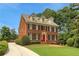 Elegant brick home featuring lush landscaping and a driveway leading to a red front door at 4045 Boles Creek Dr, Duluth, GA 30096