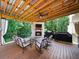 Inviting covered back deck featuring a stone fireplace, seating area, and outdoor grill, ideal for entertaining at 1630 Reindeer Rdg, Alpharetta, GA 30005