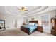 Main bedroom featuring a tray ceiling, carpet, and natural light at 1630 Reindeer Rdg, Alpharetta, GA 30005