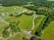 A dynamic aerial view showcases open land, scattered trees, nearby ponds, and other structures in the distance at 226 Euharlee Five Forks Rd, Kingston, GA 30145
