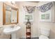 Bathroom featuring a pedestal sink, toilet, and windows with valances at 226 Euharlee Five Forks Rd, Kingston, GA 30145