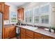 Kitchen area featuring granite countertops, stainless steel dishwasher and sink, wooden cabinets, and bright windows at 226 Euharlee Five Forks Rd, Kingston, GA 30145
