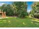 Large backyard with lush green lawn and mature trees, featuring a wooden deck with stairs at 325 Stonecastle Sw Pass, Atlanta, GA 30331