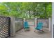 Relaxing patio featuring a gray lattice surround, wooden deck, and 2 blue chairs surrounded by lush green trees at 836 Saint Charles Ne Ave # I, Atlanta, GA 30306