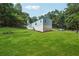 Exterior angle view shows a single story home with grass yard, trees and an adjacent gravel parking area at 4820 Scott Rd, Cumming, GA 30041