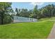 Bright, grassy lawn slopes down to a light blue single-story home with white foundation and gravel driveway at 4820 Scott Rd, Cumming, GA 30041