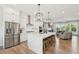 Open-concept kitchen with stainless appliances, a large island with seating, and hardwood floors that flow into the living area at 6930 Whitman Walk, Alpharetta, GA 30005
