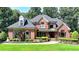 Stately brick home with manicured lawn, lush landscaping and elegant architectural details at 10020 Normandy Ln, Suwanee, GA 30024