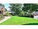 The large, lush front yard of this home boasts green grass and manicured shrubbery at 10020 Normandy Ln, Suwanee, GA 30024