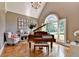 Sun-filled living room featuring hardwood floors and a piano underneath cathedral windows at 10020 Normandy Ln, Suwanee, GA 30024