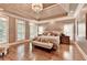 Spacious bedroom with decorative tray ceiling, large windows, and gleaming hardwood floors at 10020 Normandy Ln, Suwanee, GA 30024