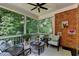A relaxing screened porch with brick accent wall overlooks a wooded backyard at 10020 Normandy Ln, Suwanee, GA 30024