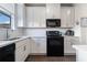 Bright kitchen featuring white cabinets, countertops, and black appliances at 160 Auburn Gate Ln, Auburn, GA 30011
