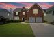 Charming two-story brick home with well-manicured lawn, mature landscaping, and two-car garage, radiating curb appeal at 5010 Amber Leaf Dr, Roswell, GA 30076
