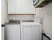 Bright laundry room with modern washer and dryer units and overhead cabinets at 5010 Amber Leaf Dr, Roswell, GA 30076
