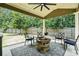 Covered patio with a stone fire pit, grill, four chairs, and a ceiling fan, perfect for outdoor gatherings at 5696 Walnut Mill Ln, Powder Springs, GA 30127