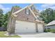 Side view of a two-story brick home showcasing the two-car garage and well-maintained landscaping at 5696 Walnut Mill Ln, Powder Springs, GA 30127