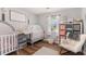 Cozy Bedroom features two white cribs, wood floors, and a comfortable rocking chair at 487 Laney Rd, Locust Grove, GA 30248