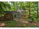 View of the home's rear exterior with a shed and patio, surrounded by lush, mature trees at 4672 Satellite Blvd, Duluth, GA 30096