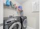 A laundry room is equipped with a modern washer and dryer set and shelving for storage at 916 Gambino Trce, Peachtree City, GA 30269