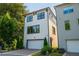 Three-story house with white siding, dark trim, brick driveway, and well-maintained landscaping at 100 Villa Magnolia Ln, Alpharetta, GA 30009