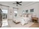 Sunlit main bedroom featuring a king bed, ceiling fan, neutral decor, and expansive windows at 100 Villa Magnolia Ln, Alpharetta, GA 30009