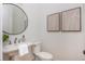 Bright powder room with pedestal sink, round mirror, decorative art and modern fixtures at 100 Villa Magnolia Ln, Alpharetta, GA 30009
