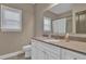Well-lit bathroom featuring a large mirror, white cabinets, modern fixtures, and tan countertops at 13015 Fox Rd, Alpharetta, GA 30005