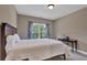Cozy bedroom with a dark wood bed frame, light colored walls, and a view of the trees from the window at 13015 Fox Rd, Alpharetta, GA 30005