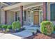Charming front porch featuring wood pillars, stone accents, manicured landscaping, and a wooden front door at 13015 Fox Rd, Alpharetta, GA 30005
