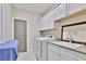 Functional laundry room with white cabinets, modern washer and dryer, and a utility sink at 13015 Fox Rd, Alpharetta, GA 30005