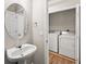 A half bath with a pedestal sink, oval mirror, and a laundry room including a washing machine and dryer in the background at 486 Windcroft Nw Cir, Acworth, GA 30101