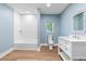 A light blue bathroom featuring a white vanity, mirror, and shower with tub at 5233 Groovers Landing Se Rd, Acworth, GA 30101