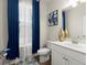 Well-lit bathroom with a vanity, blue curtains, decorative accents, and a neutral color palette at 2227 Foley Park St, Snellville, GA 30078