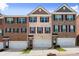 Three-story brick townhomes featuring individual garages and manicured lawns under a bright blue sky at 2227 Foley Park St, Snellville, GA 30078