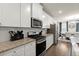 Modern kitchen featuring stainless steel appliances, granite countertops, and white cabinets, plus a view to the dining area at 2227 Foley Park St, Snellville, GA 30078