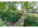 A serene backyard featuring a charming bridge over a creek, lush greenery, and landscaping leading up to the home at 3219 Parkridge Crescent, Chamblee, GA 30341