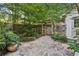 Stone patio area with wooden gate, lush landscaping, and a tranquil setting in the backyard at 205 Pine Lake Dr, Cumming, GA 30040