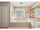Well-lit bathroom features a soaking tub, double vanity, and large window for natural light at 205 Pine Lake Dr, Cumming, GA 30040
