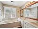 Bright bathroom featuring a soaking tub, double vanity, and a large mirror above the sink at 205 Pine Lake Dr, Cumming, GA 30040
