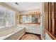 Bright bathroom with a soaking tub, double vanity, and large mirror, with a view to the bedroom at 205 Pine Lake Dr, Cumming, GA 30040