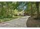 A long driveway leads up to this traditional style home nestled among mature trees and lush landscaping at 205 Pine Lake Dr, Cumming, GA 30040
