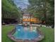 A gorgeous pool with a built-in jacuzzi, stone surround, waterfalls, patio, and backyard with lush landscaping at 205 Pine Lake Dr, Cumming, GA 30040